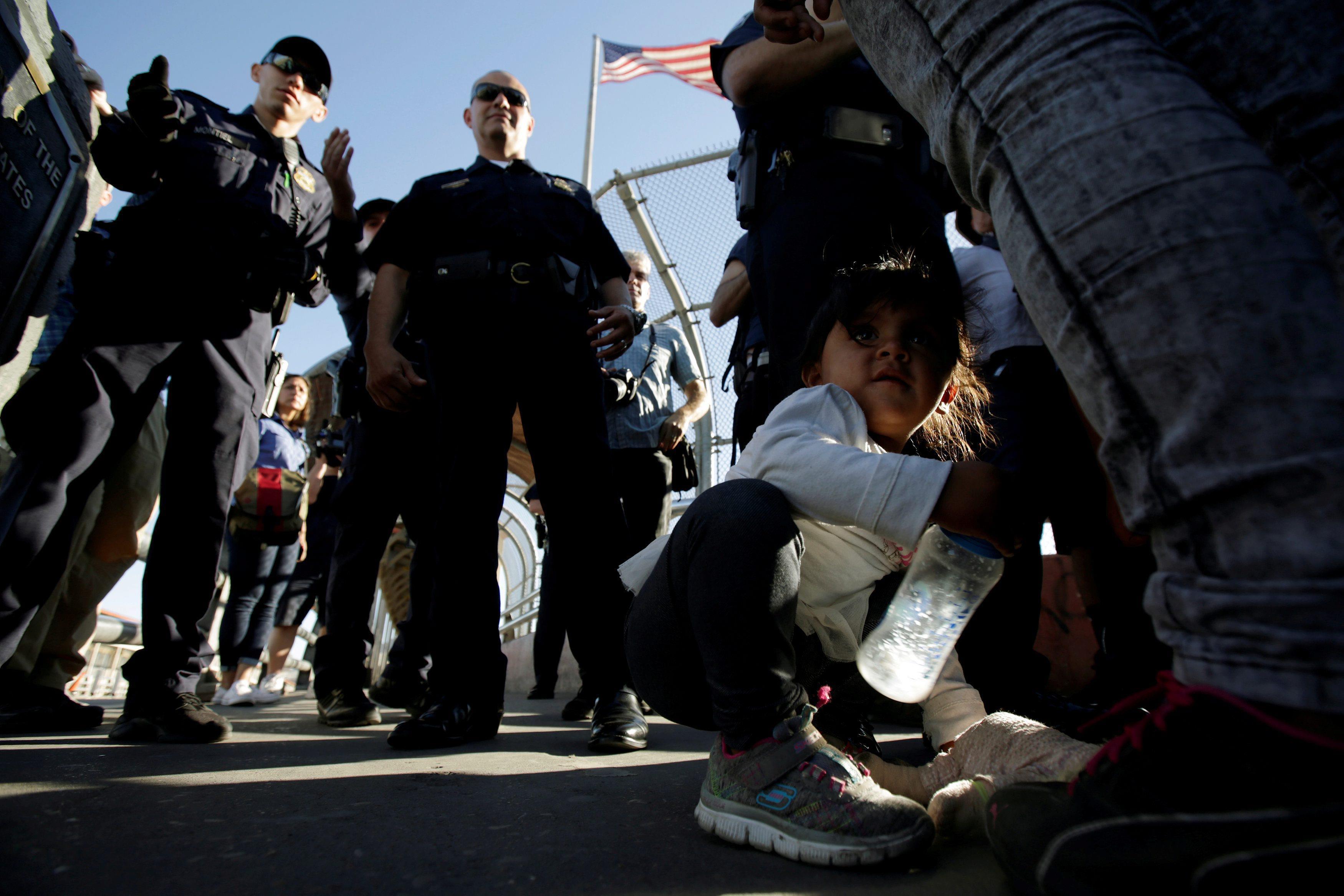 Migrant families from Mexico listen to officers of the U.S. Customs and Border Protection before ent