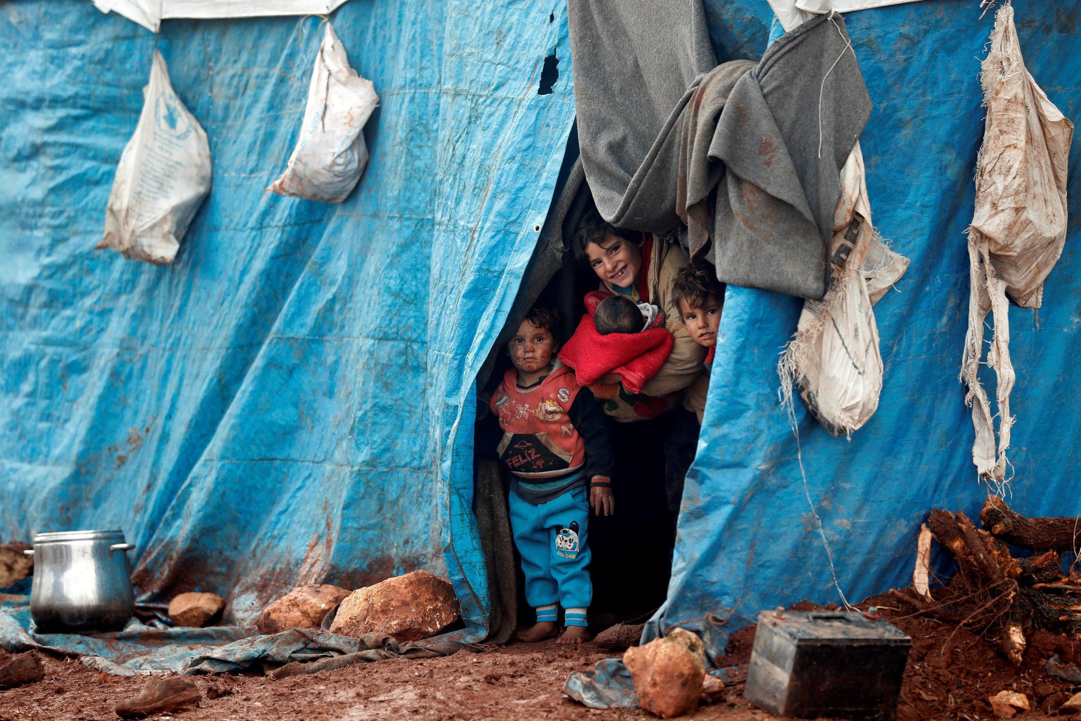 Displaced Syrian children look out from their tents at Kelbit refugee camp in Idlib province