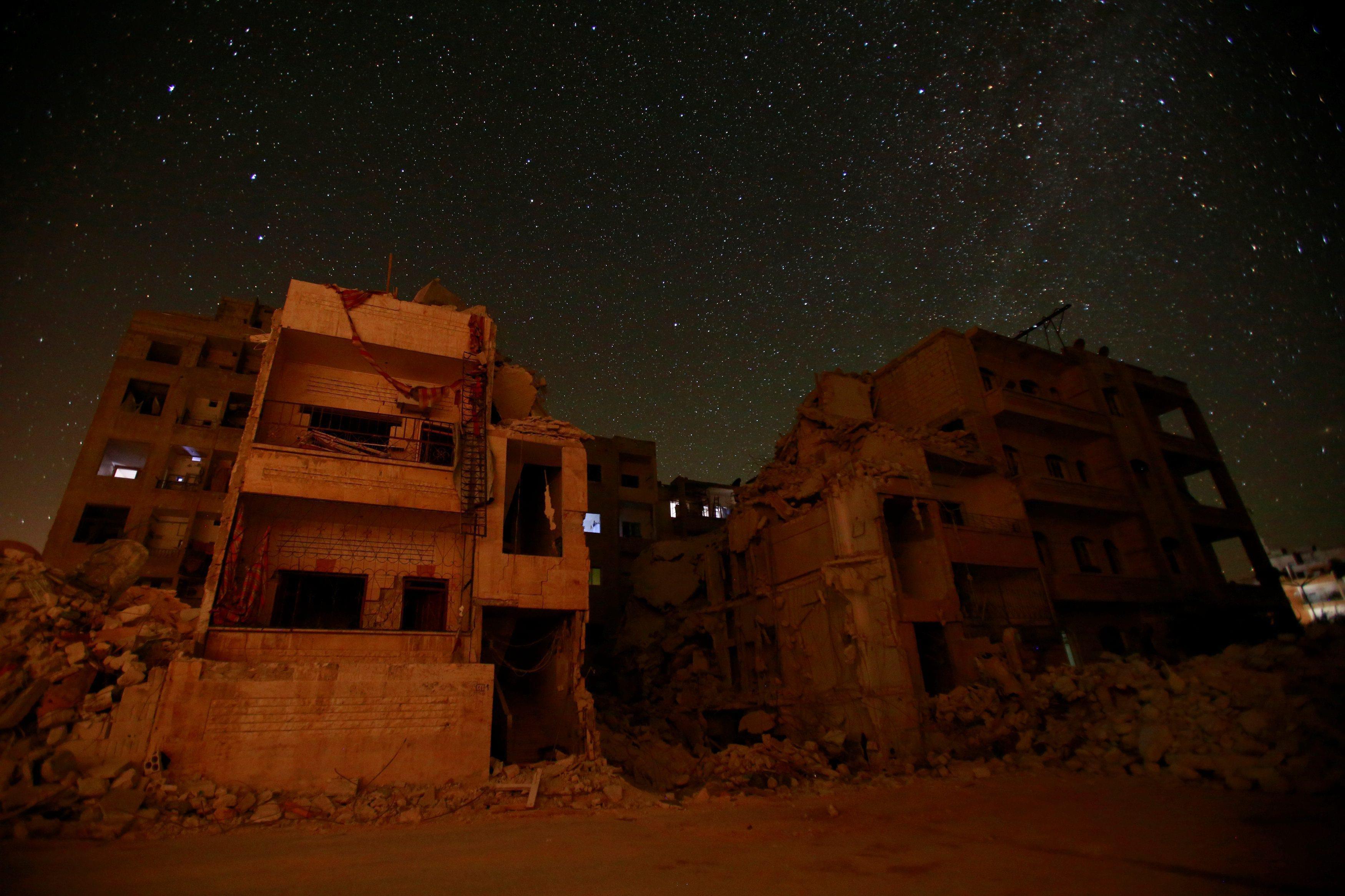 Damaged buildings are pictured at night in Idlib city