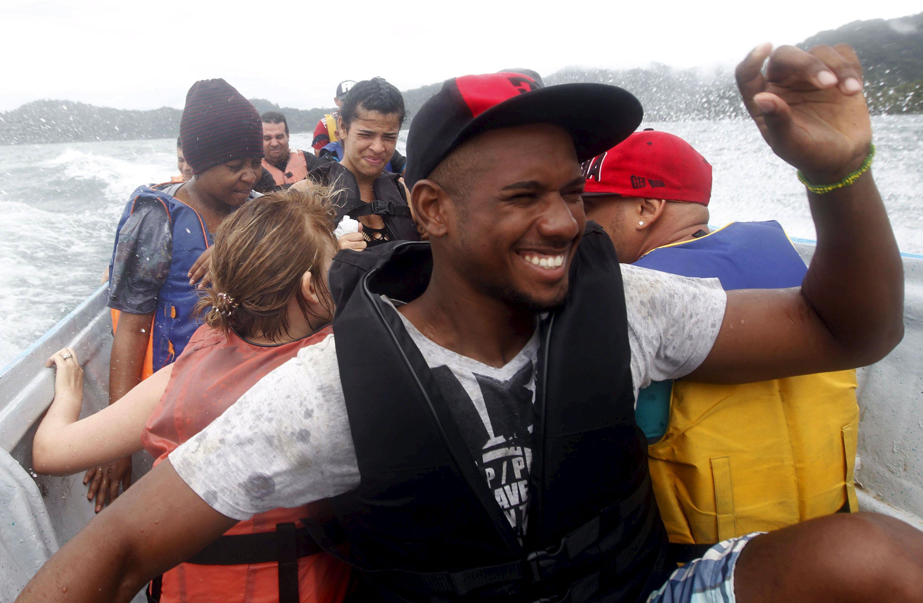 Cuban migrants brace themselves against the spray as they continue their journey to the north by boa