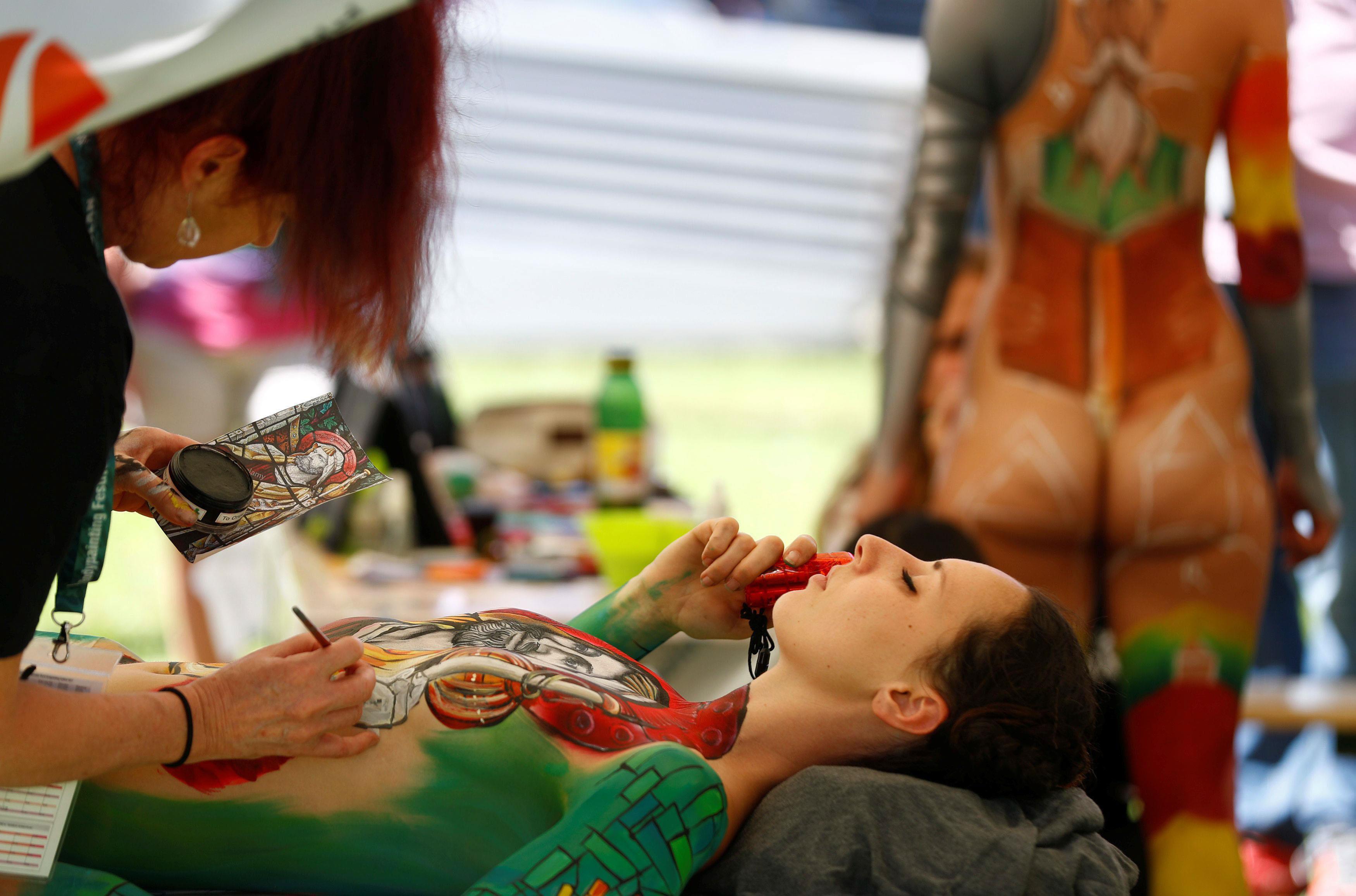 An artist touches up makeup on a model during the 