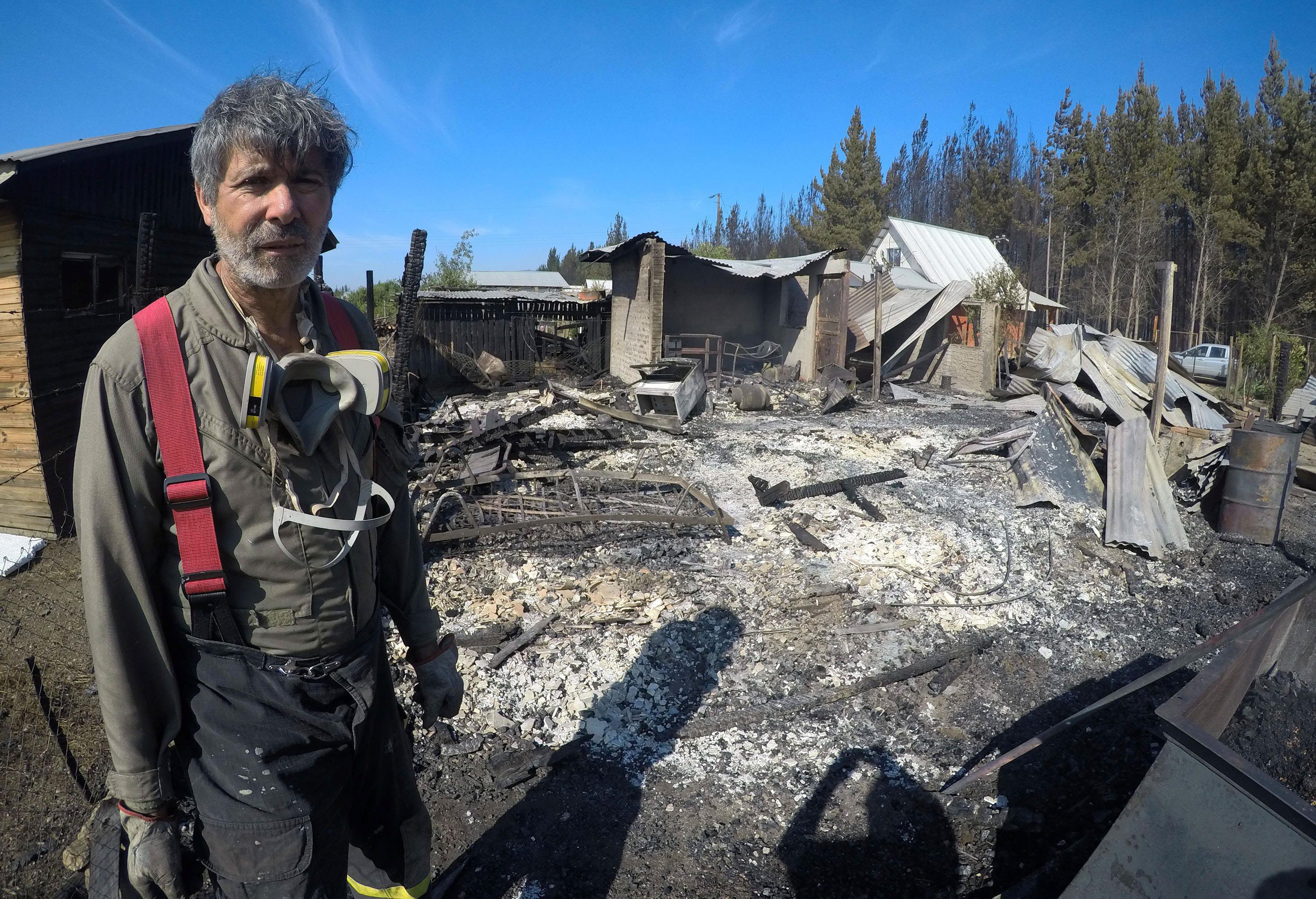 A firefighter stand next to burnt houses after a forest fire in the town of Nirivilo in the Maule re