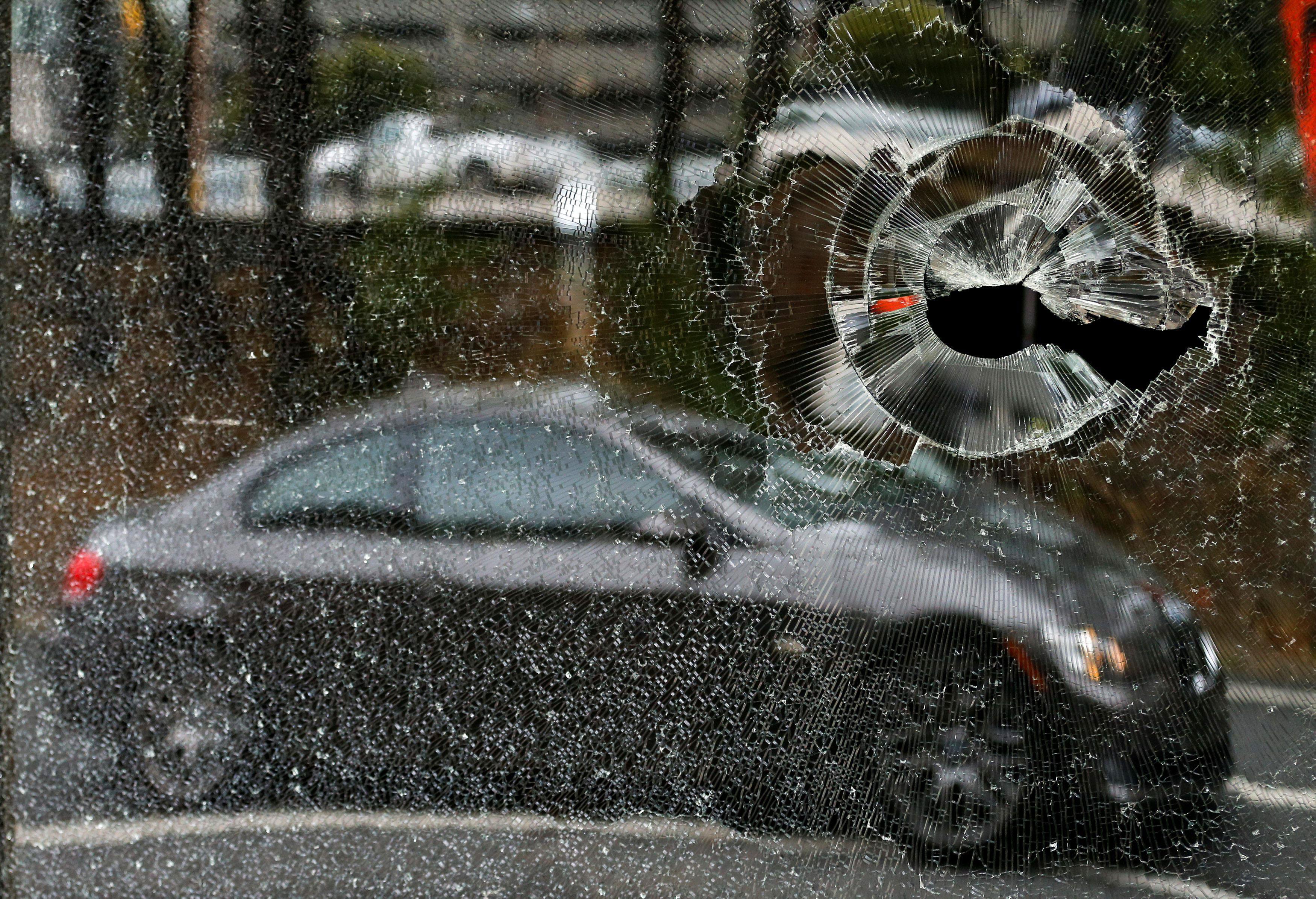 A car is reflected in a damaged window to a building after protests against the police shooting of K