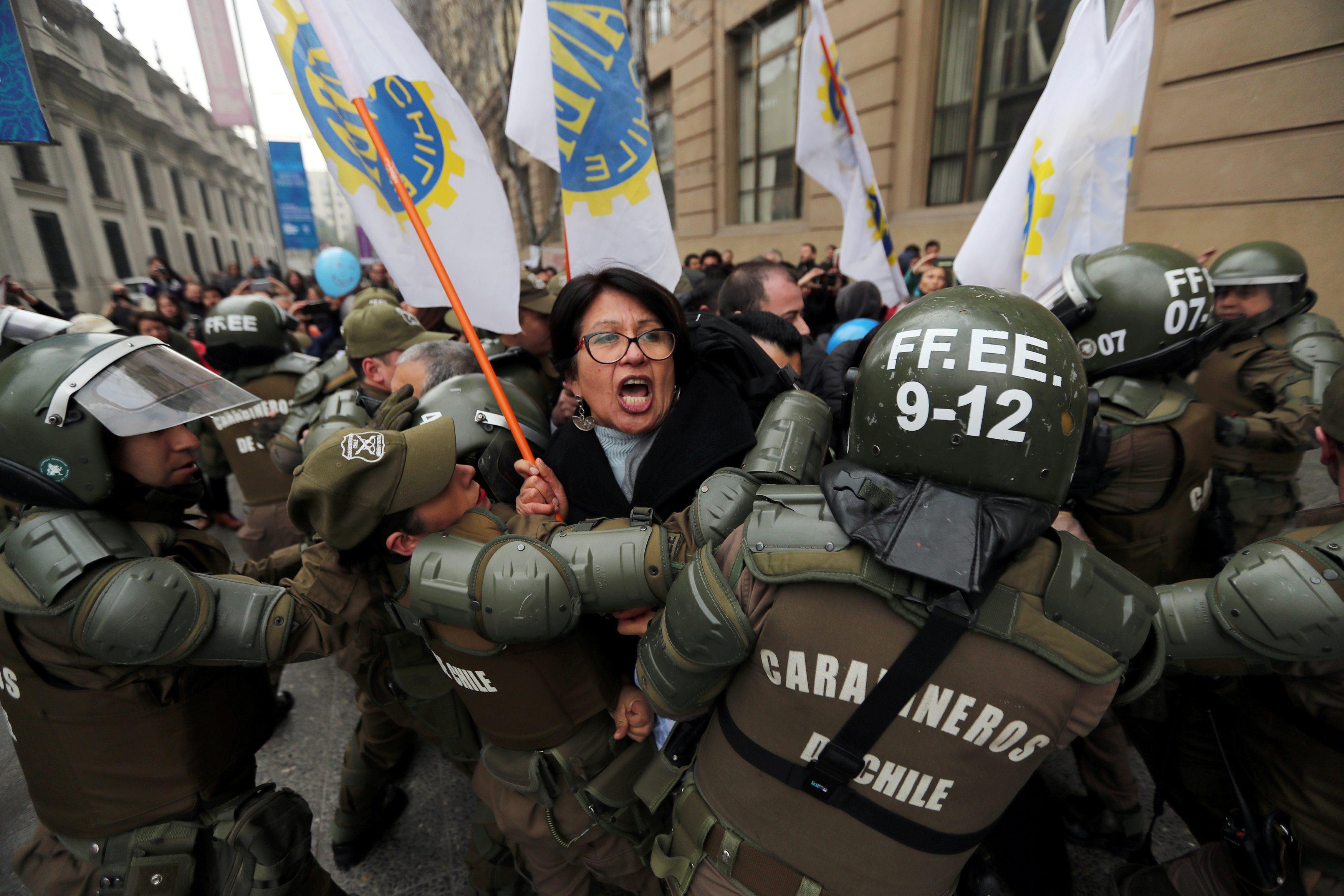 Riot policemen block the way of protesters during a demonstration in Santiago