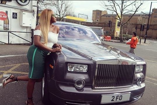 DJ Cuppy posing with had dad's Rolls Royce
