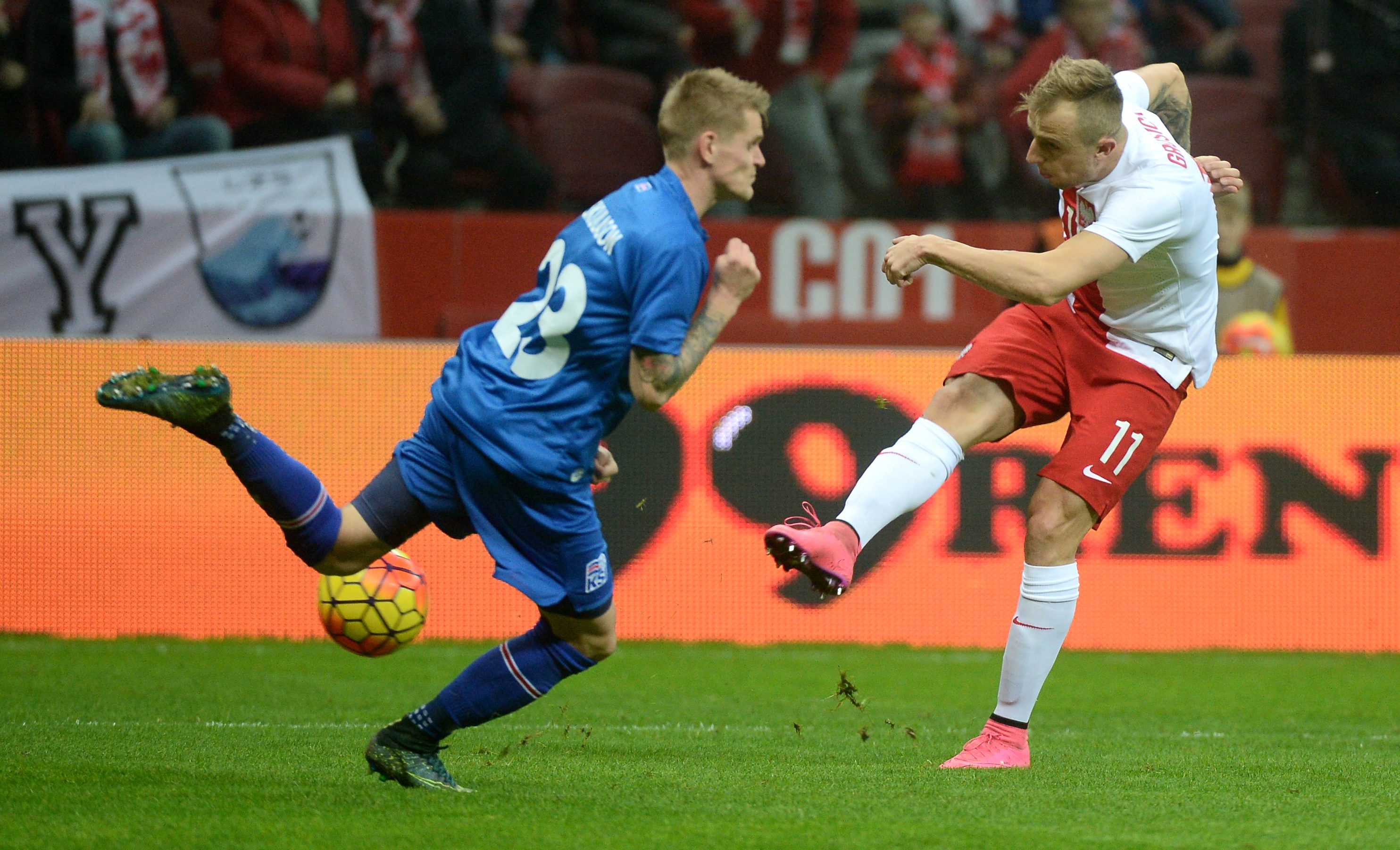 Kamil Grosicki (P) strzela obok Islandczyka Ariego Freyra Skulasona (L) podczas meczu towarzyskiego w Warszawie