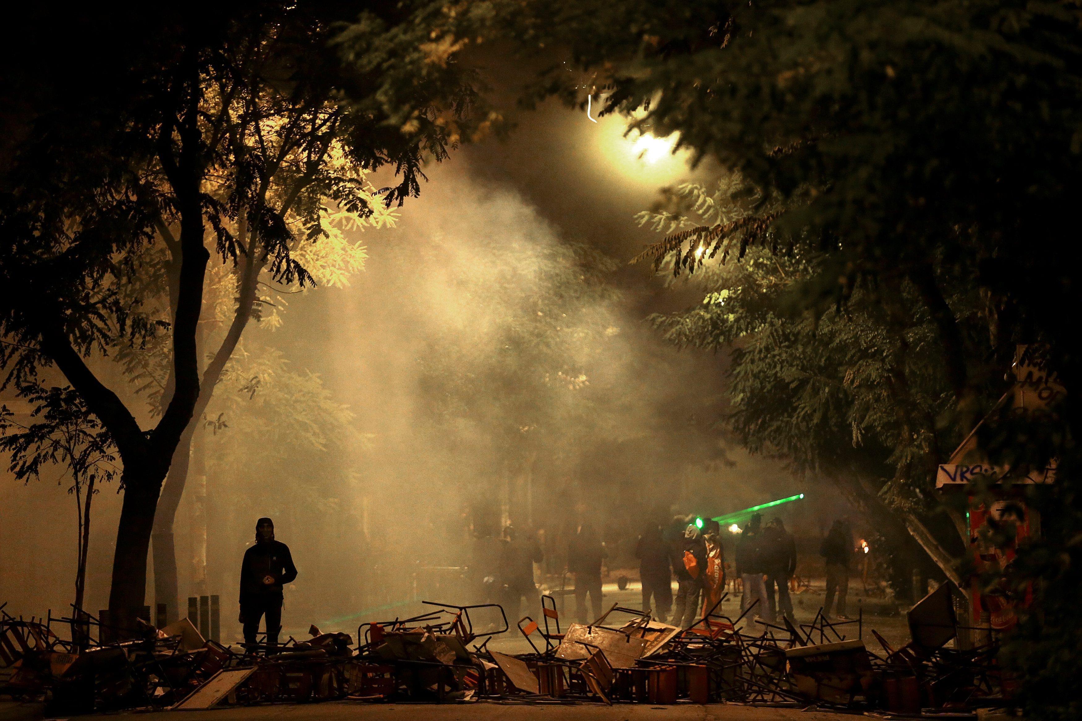 Hooded protesters walk amid smoke during clashes following a rally marking the 43nd anniversary of a