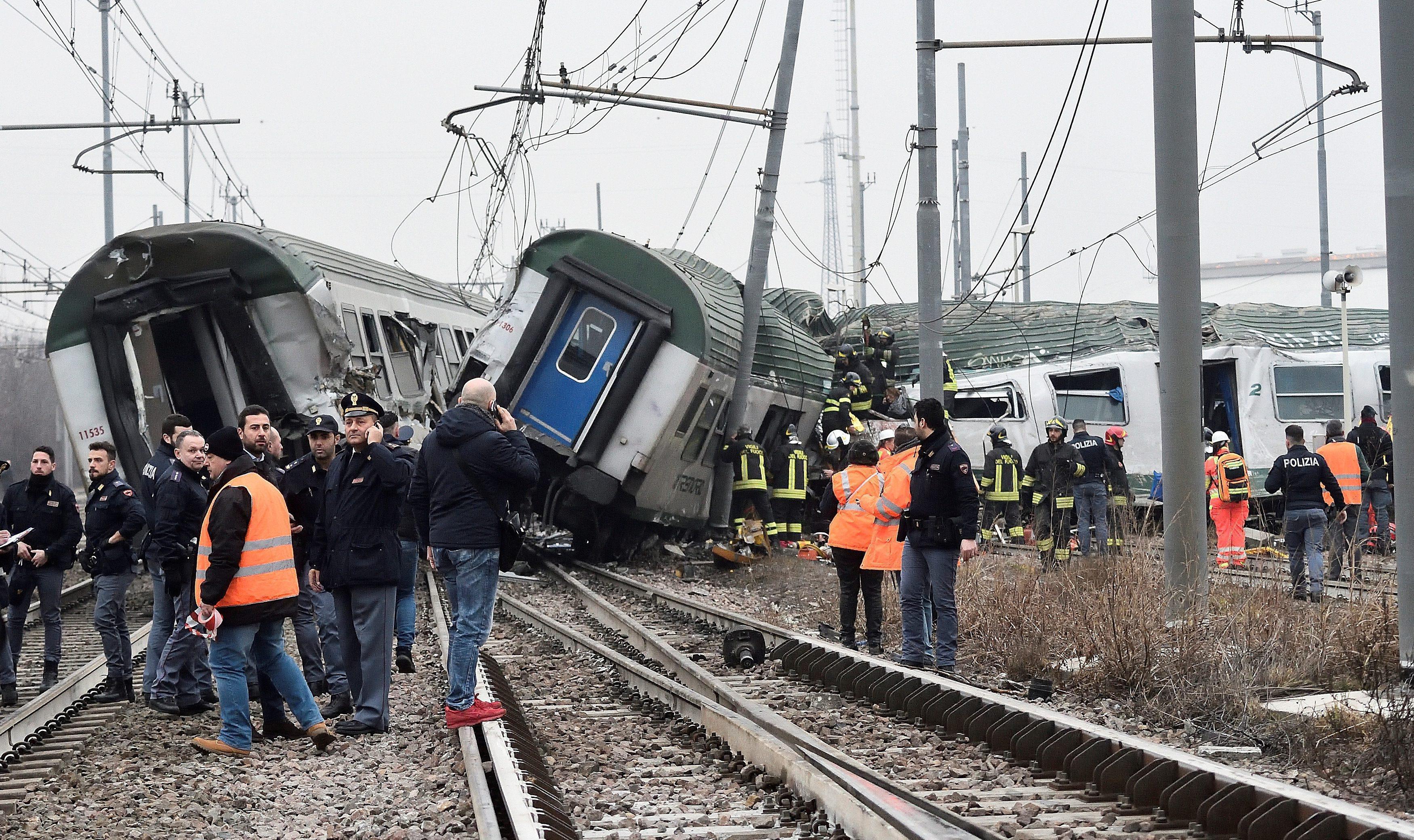 Rescue workers and police officers stand near derailed trains in Pioltello, on the outskirts of Mila