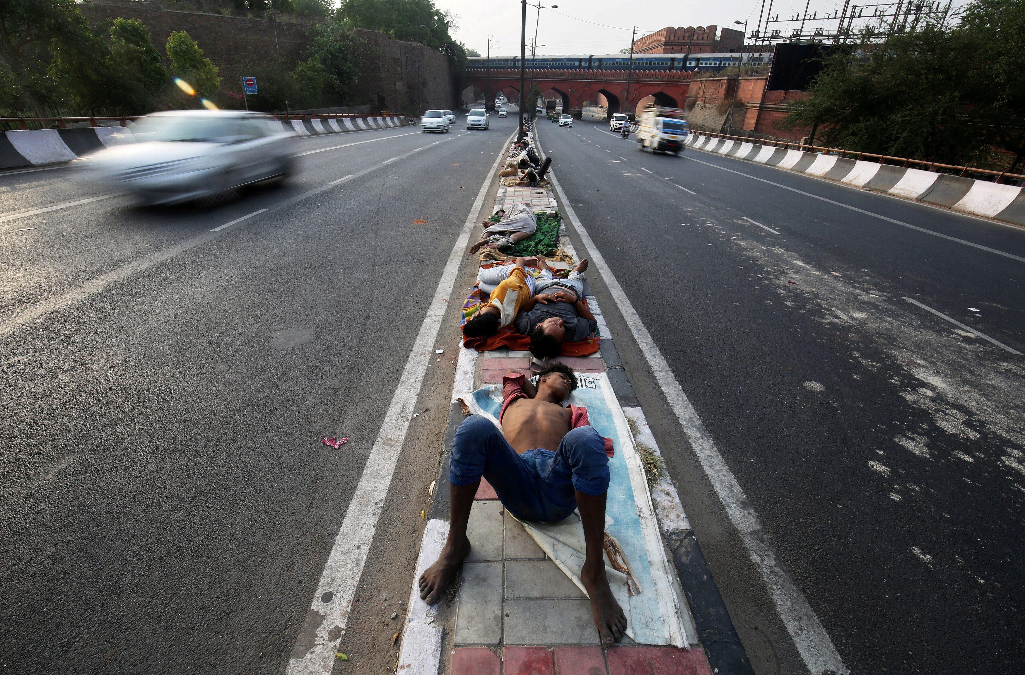 People sleep on a road divider in New Delhi
