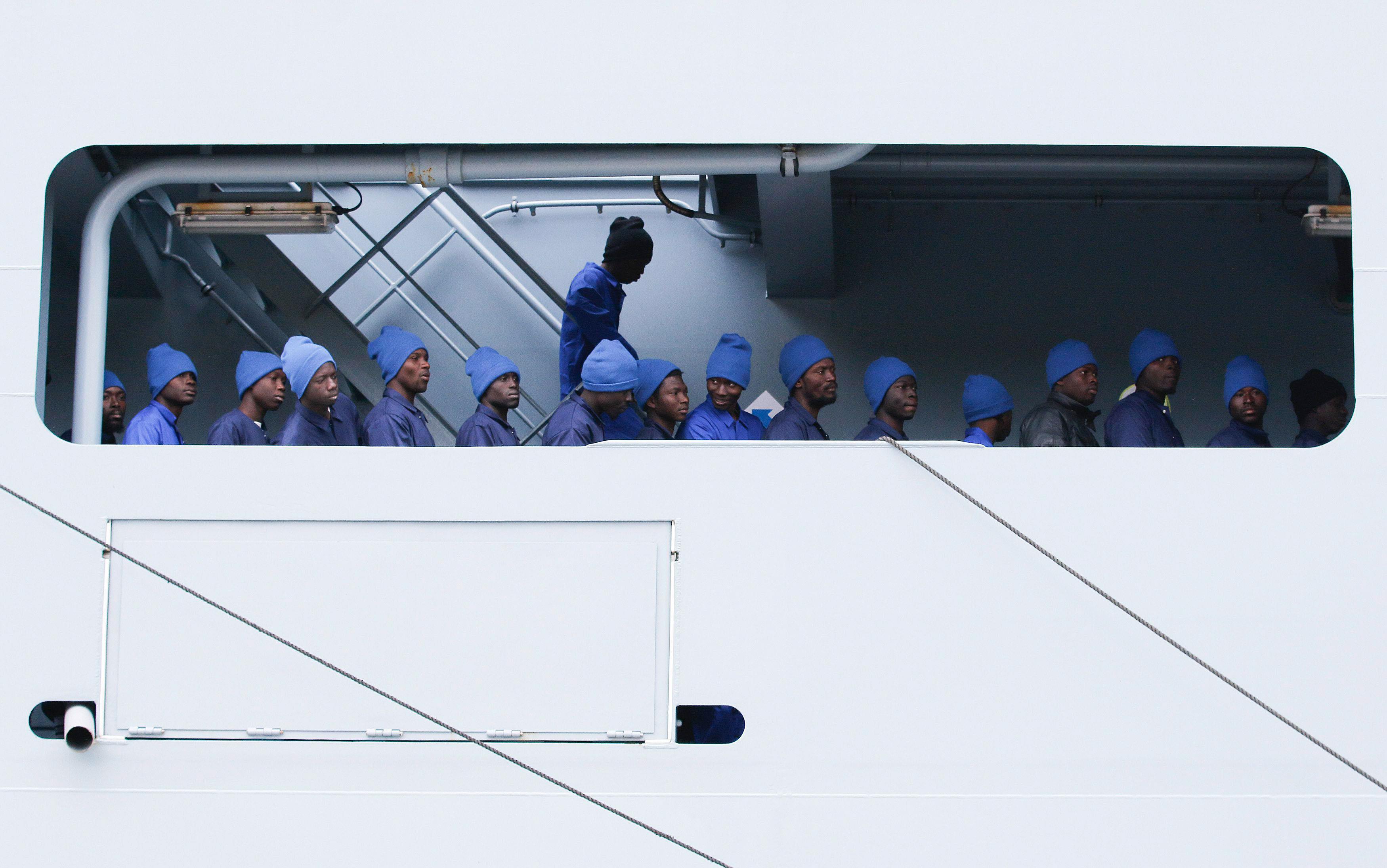 Migrants line up as they disembark the German naval vessel Frankfurt Am Main in the Sicilian harbour