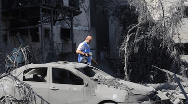 Egy ENSZ-alkalmazott sétál az izraeli bombázások során lerombolt épületek romjai között a Gázai övezet déli részén fekvő Khan Juniszban, az Izrael és a Hamász palesztin csoport között zajló harcok közepette. /Fotó-illusztráció: Ahmed Zakot/SOPA /GettyImages