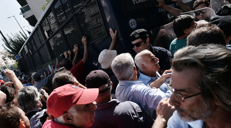 A görög fővárosban nyugdíjukért tüntető idős emberek így próbálták a rendőrök mellett felborítani a hatalmas járművet / Fotó: AFP