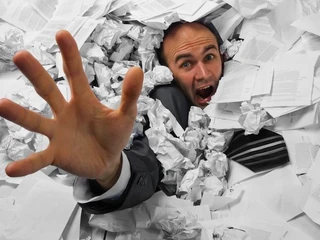 Businessman sinking in heap of documents