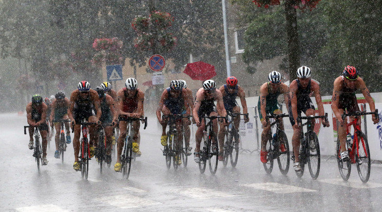 Heves esőben kerékpározik a tiszaújvárosi triatlon-világkupa férfi döntőjének mezőnye 2018. július 8-án. A férfi döntő a jégeső miatt félbeszakadt, a viadalt nem folytatták. / Fotó: MTI: Vajda János