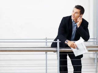 Businessman using mobile while leaning on a railing - Copyspace