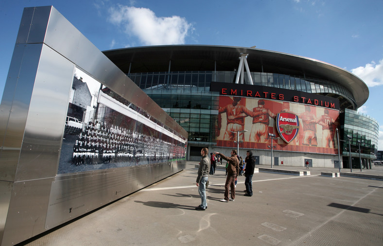 Turyści oglądają zdjęcie byłych graczy klubu piłkarskiego Arsenal obok stadionu Emirates Stadium w Londynie, Wielka Brytania