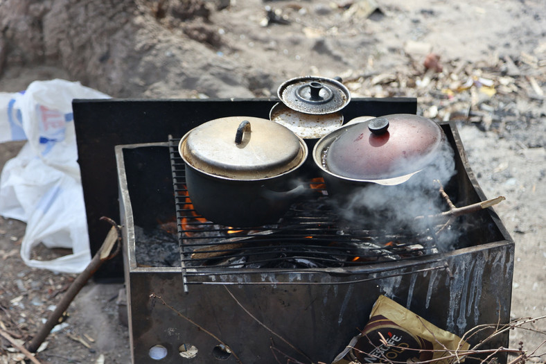 Cywile gotują posiłek wśród gruzów w Mariupolu 