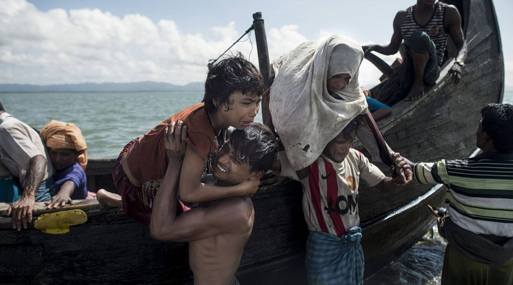 Bangladeshi férfi segíti ki a rohingya menekülteket egy csónakból / Fotó: AFP