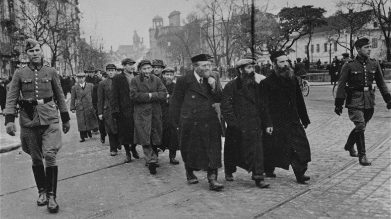 Żydzi eskortowani przez niemiecką policję do pracy przymusowej. Krakowskie Przedmieście w Warszawie, marzec 1940 r.
