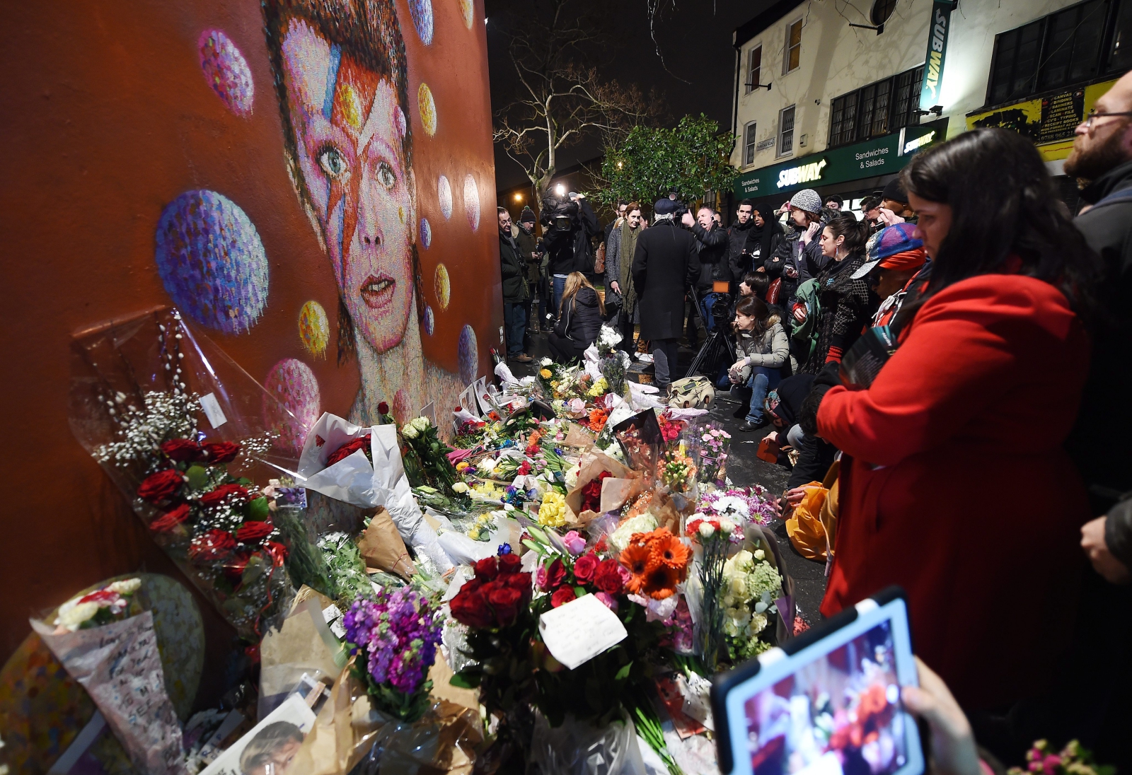 Fani składają kwiaty pod muralem poświęconym Bowiemu w jego rodzinnym Brixton