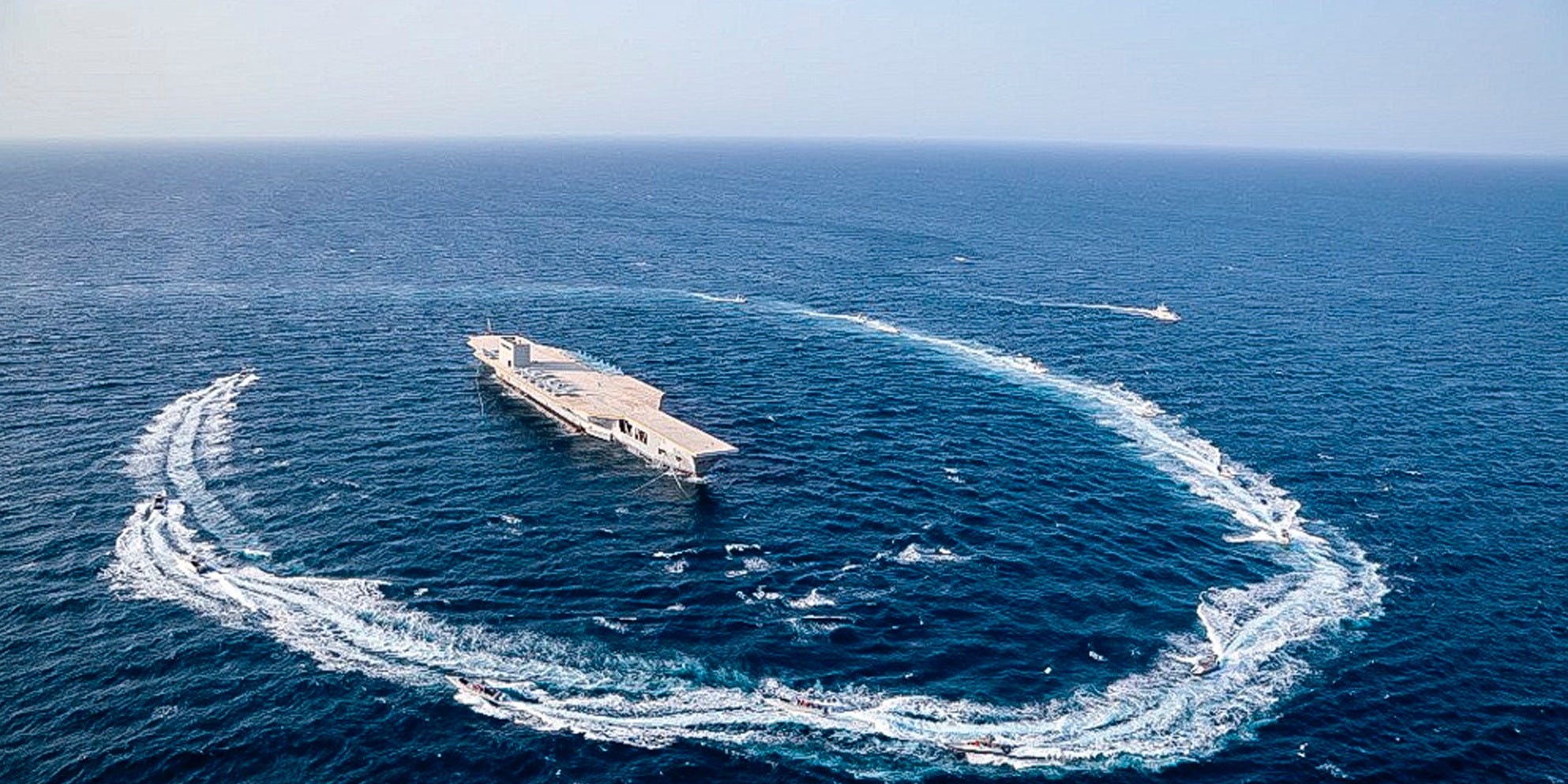 Revolutionary Guard speedboats circle around the replica aircraft carrier in the Strait of Hormuz on July 28, 2020.