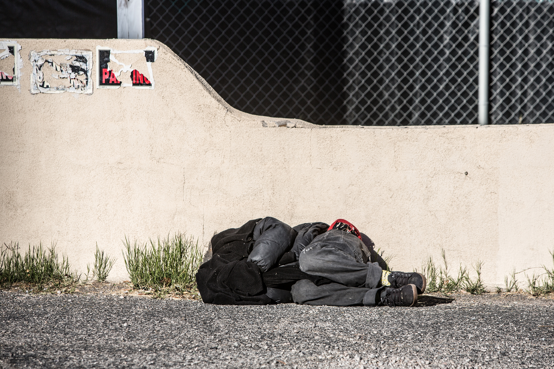 Near the wall. Бездомный фотосток. Бездомные спят на улице в жарких странах.