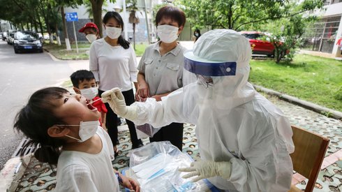 Wuhan. Pracownik medyczny pobiera próbkę wymazu od dziecka w celu zbadania na obecność koronawirusa. Fot. STR / AFP 