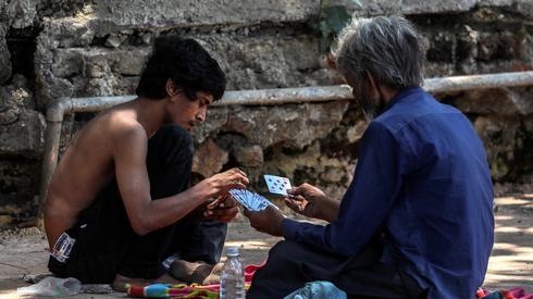 Hindusi grają w gry karciane na ulicy podczas awaryjnej blokady z powodu koronawirusa w Mumbaju w Indiach. Stan Maharashtra ogłosił blokadę do 30 kwietnia 2020 r., Aby powstrzymać rozprzestrzenianie się COVID-19 . Fot. PAP /  EPA / Divyakant Solanki