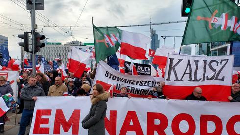 Nad głowami zgromadzonych powiewają także flagi z symbolami Młodzieży Wszechpolskiej oraz innych organizacji narodowych. Nie brakuje czerwonych sztandarów z białym orłem. Niektórzy z uczestników mają białoczerwone opaski na ramionach, inni poprzypinali do kurtek kotyliony.