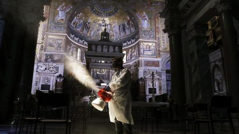 Pracownik w kombinezonie ochronnym dezynfekuje bazylikę św. Marii na Zatybrzu (Rzym) Foto: PAP / Riccardo Antimianti