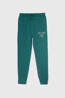 Spodnie i spodenki dla dziewczynek - Guess spodnie dresowe bawełniane dziecięce kolor zielony z nadrukiem - grafika 1