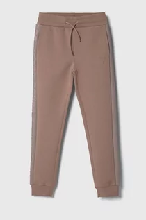 Spodnie i spodenki dla dziewczynek - Guess spodnie dresowe dziecięce kolor różowy gładkie - grafika 1