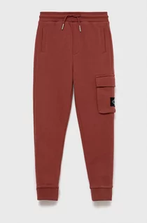 Spodnie i spodenki dla chłopców - Calvin Klein Jeans Jeans spodnie dresowe dziecięce kolor pomarańczowy gładkie - grafika 1