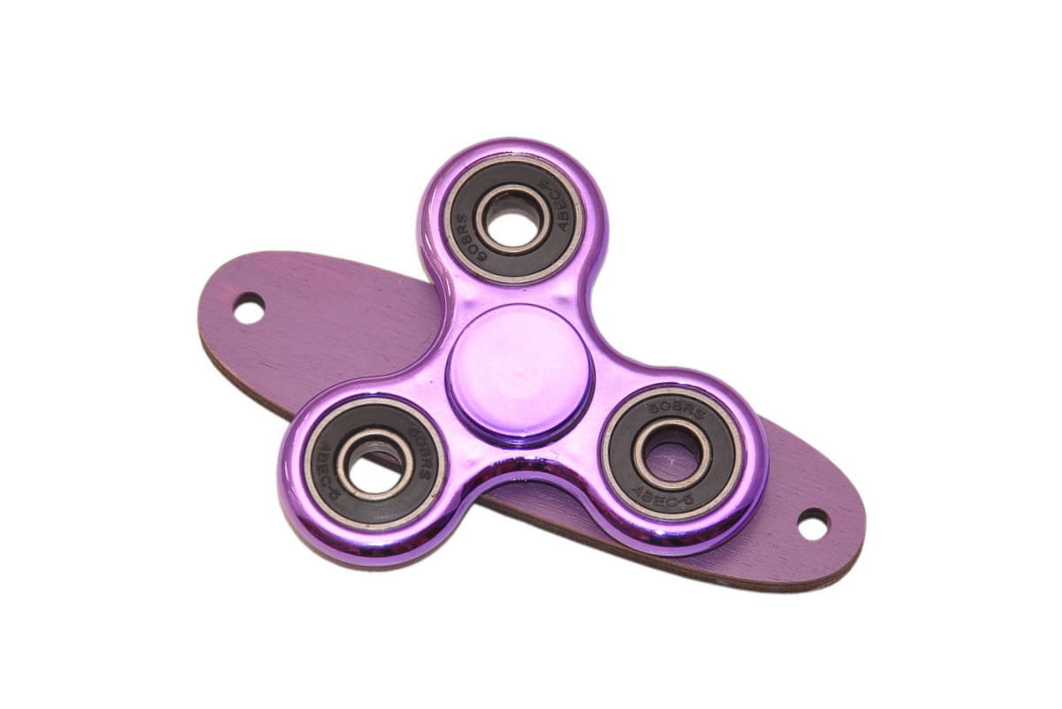 Fioletowy spinner do tablicy sensorycznej na fioletowej podstawce.