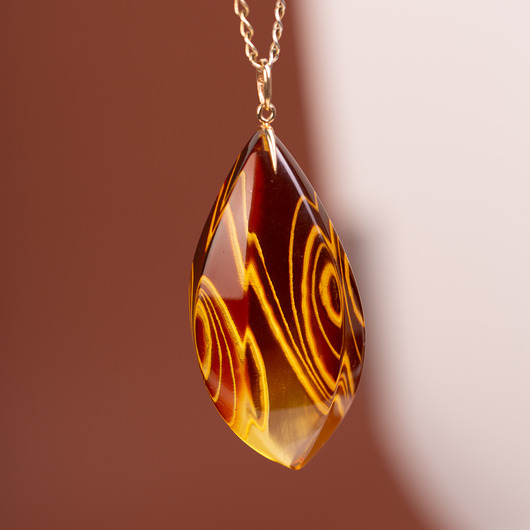 Złoty wisiorek z rzeźbionym bursztynem barwionym
