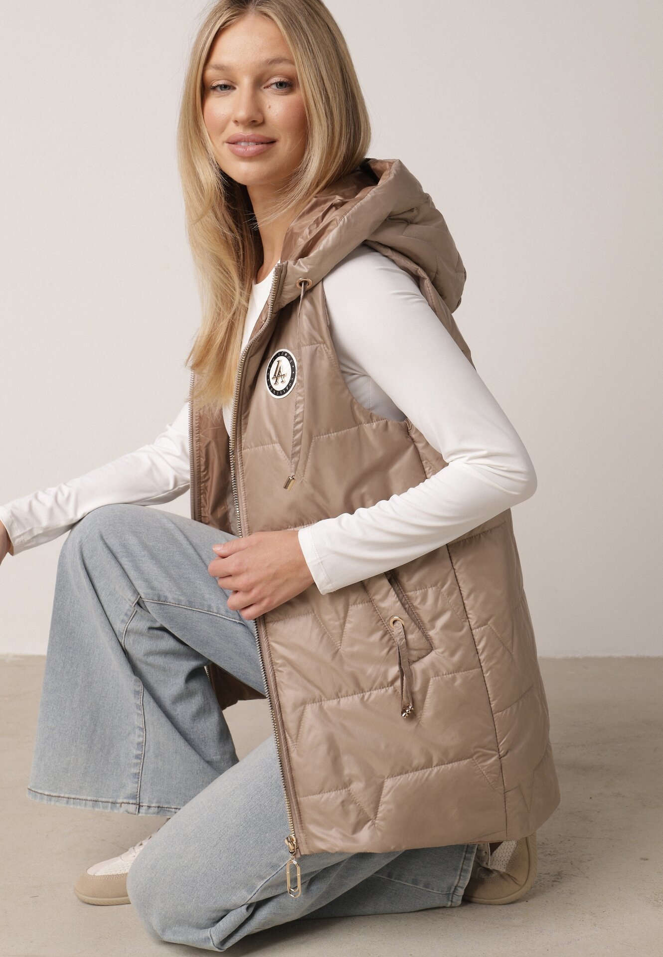 Brązowa Pikowana Kamizelka o Długim Kroju z Nieodpinanym Kapturem i Aplikacją Koretes