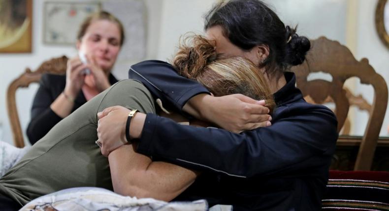 (L to R) Rita Hitti (mother of 27-year-old missing fireman Najib) and her daughter Carlyn (wife of 37-year-old missing fireman Charbel Karam) cry as they comfort each other at their home in the mountain town of Qartaba, north of the Lebanese capital