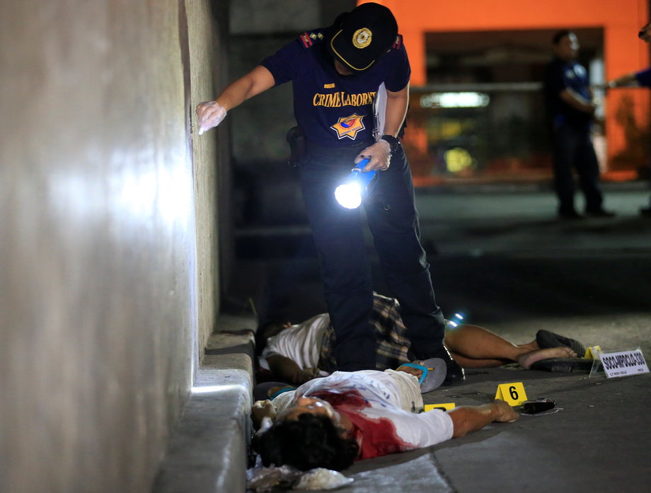 A police investigator inspects the corpse of a man they say was a drug pusher, during a drug-bust police operation in Santa Cruz city, metro Manila, Philippines, November 17, 2016.