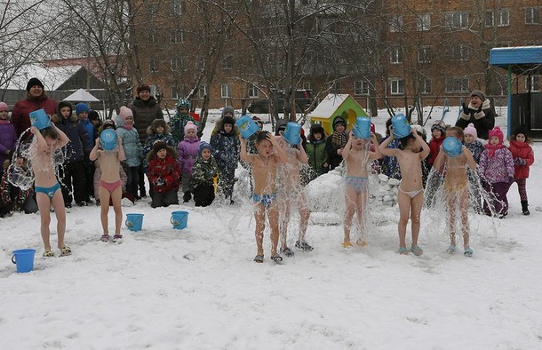 Children watch their classmates pour cold water on themselves, under the watch of fitness coach Oksa