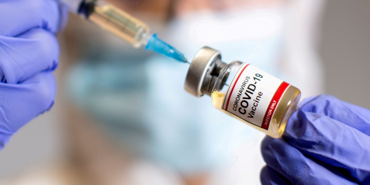 FILE PHOTO: A woman holds a medical syringe and a small bottle labeled "Coronavirus COVID-19 Vaccine