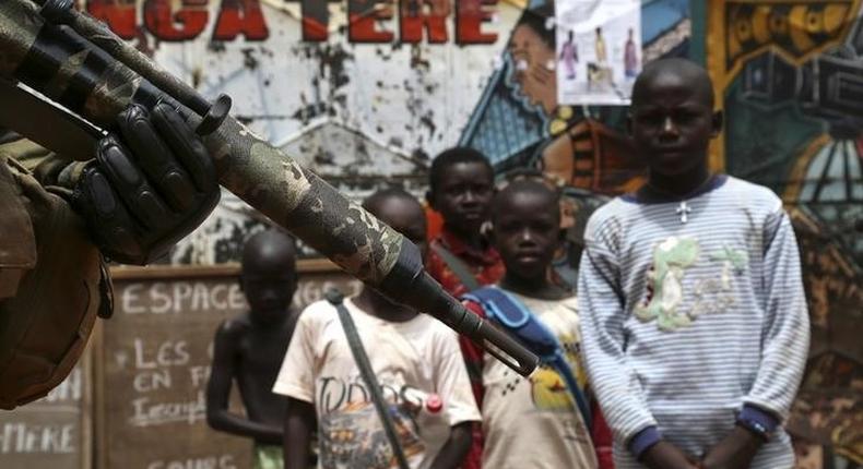 Children look at a soldier from the newly deployed EUFOR-RCA European Union military operation in the Central African Republic, patrolling along a street in Bangui May 8, 2014. REUTERS/Emmanuel Braun