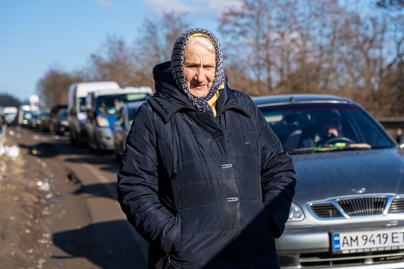 Wiele osób spaceruje niedaleko swoich pojazdów