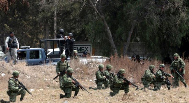 Soldiers take positions in front of villagers mounting roadblocks with burning tires to protest an army crackdown the day after a clash between soldiers and alleged fuel thieves on May 4, 2017