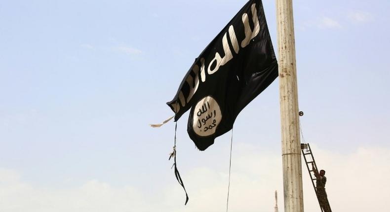 A member of the US-backed Syrian Democratic Forces, made up of Arabs and Kurds, removes an Islamic State group flag in the Syrian town of Tabqa on April 30, 2017