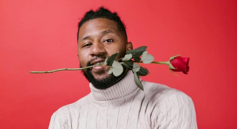 Man in white turtleneck sweater holding red rose [Image Credit: RDNE Stock Project]