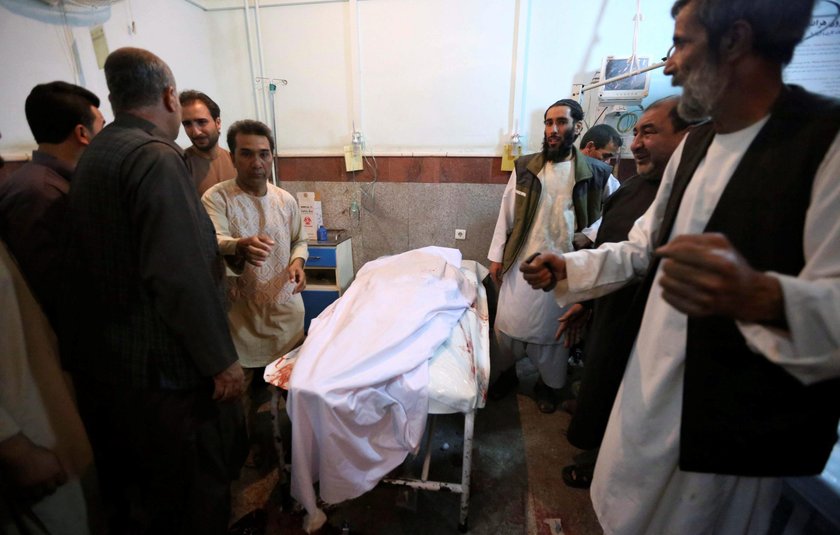 Afghan policemen and relatives inspect at the site of a suicide attack in Herat, Afghanistan