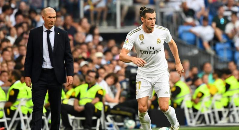 Far apart: Zinedine Zidane watches Gareth Bale