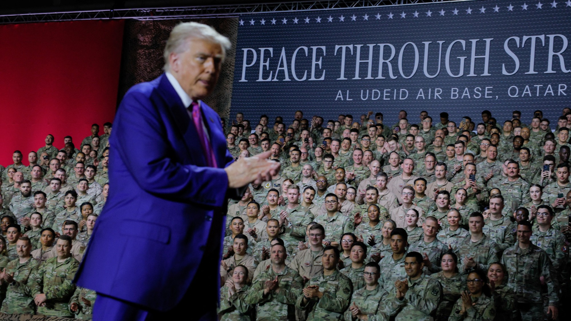 Americkí vojaci reagujú na prezidenta Donalda Trumpa, ktorý ide predniesť svoj prejav, pri transparente s nápisom „Mier prostredníctvom sily“ počas návštevy leteckej základne Al Udeid v katarskej Dauhe.