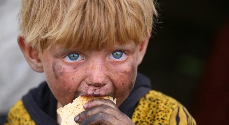 A displaced Syrian child eats at a temporary camp in the village of Ain Issa on May 1, 2017. People have been arriving at the camp for months, but the pace has picked up as the Syrian Democratic Forces militia presses its offensive against IS