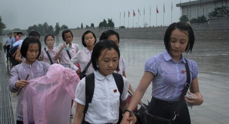 Students walk through the rain to pay their respects to late North Korean leaders Kim Il-Sung and Kim Jong-Il outside Kumsusan Palace as the country marks 'Victory Day' in Pyongyang